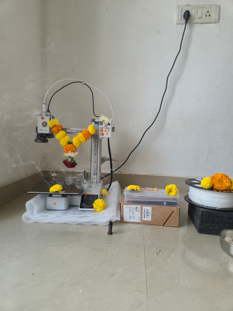 A 3D printer decorated with marigold flowers in the Spool & Spark studio